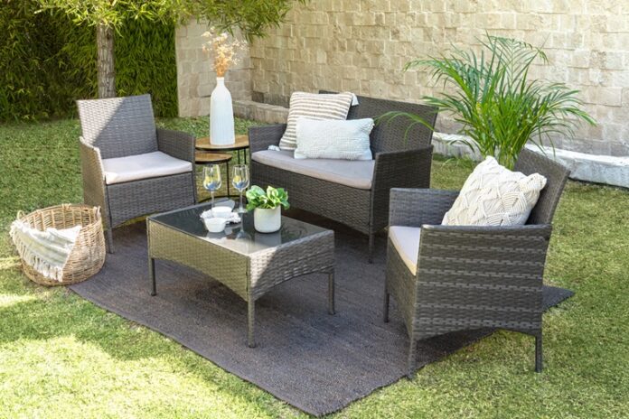 A modern outdoor rattan furniture living room set in a lush green grassy landscape